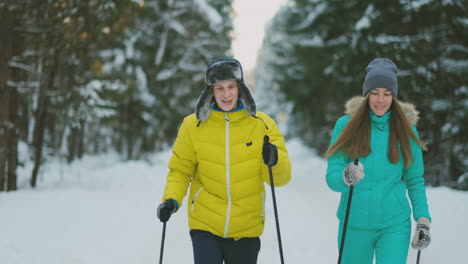 Porträt-Eines-Ehepaares.-Ein-Mann-In-Einer-Gelben-Jacke-Und-Eine-Frau-In-Einem-Blauen-Overall-Im-Winter-Im-Wald-Beim-Skifahren-In-Zeitlupe